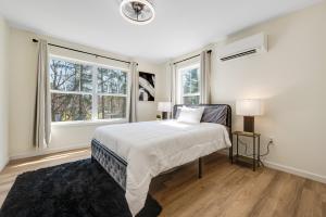 a white bedroom with a bed and two windows at Amazing Entire Townhouse Sleeps 20 Group Favorite in Bloomfield