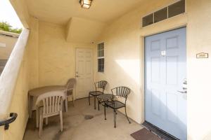 a porch with chairs and a table and a door at Sandbar Escape in Oceano