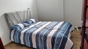a bed with blue and white striped sheets and pillows at Amaru 