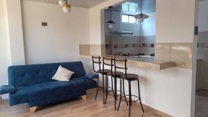 a living room with a blue couch and a kitchen at Amaru 