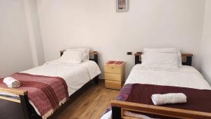 een slaapkamer met 2 bedden en een nachtkastje met een lade bij Chakana Wasi in Calca