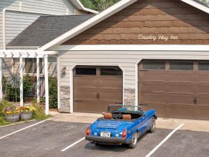 a blue car parked in a parking lot in front of a garage at Country Way Inn in Kalispell