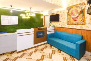 KhandagiriHotel O Sawan INN的一间设有蓝色椅子和电视的等候室 更多24张照片