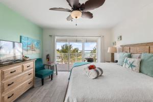 a bedroom with a bed with a ceiling fan and a television at The Starfish at Cottages in Sand Bluff