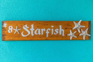 ein Holzschild mit Seesternen an einer blauen Wand in der Unterkunft The Starfish at Cottages in Sand Bluff