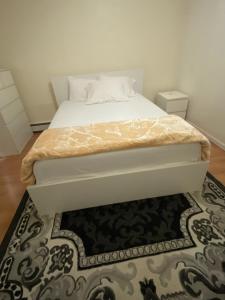 a bedroom with a white bed with a rug at private room in Paterson +1 photo