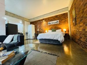 a bedroom with a bed and a brick wall at The Nook at Maboneng -24hr security, WiFi, cozy home in Johannesburg