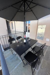 a black table with chairs and an umbrella on a balcony at Casa PORTA LANERO di Francesco e Alessandro in Nizza Monferrato +3 photos