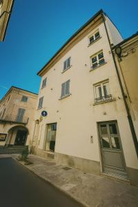 a white building with a green door on a street at Casa PORTA LANERO di Francesco e Alessandro in Nizza Monferrato