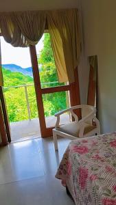 a bedroom with a bed and a chair and a window at Xixo Casa do Vale Descanso e Natureza Em Gramado in Gramado