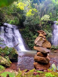 a stack of rocks in front of a waterfall at Xixo Casa do Vale Descanso e Natureza Em Gramado in Gramado