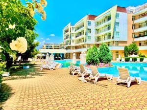 Un grupo de sillas y sombrillas junto a una piscina. en Grand Kamelia apartments, en Sunny Beach