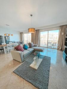 Panoramic Sea Views 3 Bedroom Apartment in St Julians S13 في سانت جوليانز: غرفة معيشة مع أريكة وطاولة زجاجية