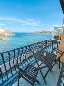 a table and chairs on a balcony overlooking the ocean at Panoramic Sea Views 3 Bedroom Apartment in St Julians in St Julian's