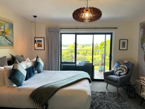 a bedroom with a large bed and a chair at Incredible mountain & sea views in Mapua