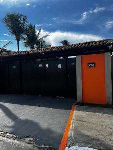 een gebouw met een oranje deur en palmbomen bij Casa Duplex com 02 suites completa em Condomínio com Piscina , Sauna , churrasqueiras, deck podendo parar embarcações, próximo as Praias das Conchas e Peró e também linda Ilha do Japônes in Cabo Frio