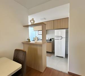 uma cozinha com uma geladeira branca e armários de madeira em Plano 22 Prime Loft em Extrema