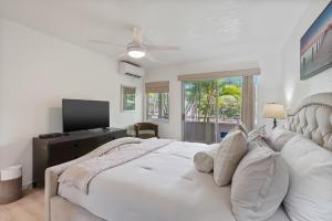 a white bedroom with a large bed and a flat screen tv at Kahaki Hale in Kapaa +10 photos