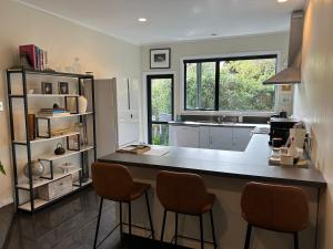 a kitchen with a counter and two stools at Incredible mountain & sea views in Mapua