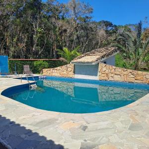 a swimming pool with a stone wall around it at Maitinga, a little paradise in Bertioga