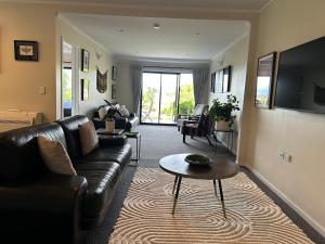 a living room with a couch and a table at Incredible mountain & sea views in Mapua