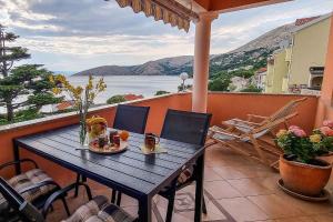 a table on a balcony with a view of the water at Apartments in Stara Baska - Insel Krk 34433 in Stara Baška