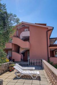 two white lounge chairs sitting in front of a building at Apartments in Stara Baska - Insel Krk 34433 in Stara Baška +5 photos
