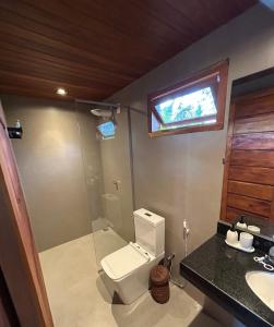 TV y baño con aseo y lavamanos. en Corumbau Bangalôs, en Prado