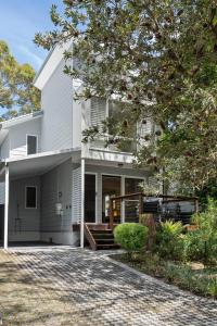ein weißes Haus mit einer Auffahrt davor in der Unterkunft Scribbly Gums Callala Beach in Callala Beach
