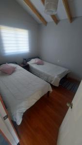 two beds in a small room with a window at Huella de Luna in Valdivia +6 photos
