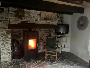 a stone fireplace with a fire in a room at La maison d olivier in Sébrazac