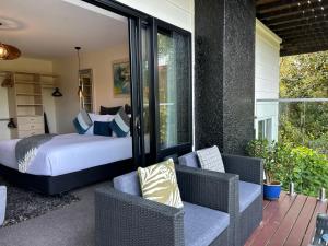 1 dormitorio con 1 cama y sillas en el patio en Incredible mountain & sea views, en Mapua