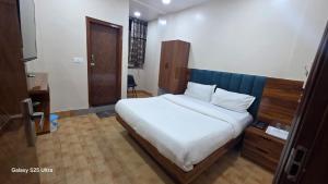 a bedroom with a large white bed with a wooden headboard at fab THE MALEEN New Delhi in New Delhi