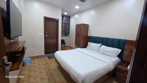 a bedroom with a large white bed and a television at fab THE MALEEN New Delhi in New Delhi +8 photos