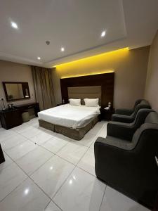 a hotel room with a bed and two chairs at ورد للشقق المخدومة - احد رفيدة in Ahad Rafidah