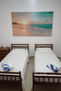 two beds in a room with a painting on the wall at Pousada Mahalo in Guarujá