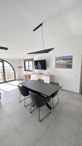 een eetkamer met een zwarte tafel en stoelen bij Villa Sotavento Ocean Views Modern New Apartment in Natural Park in Playa Jandia