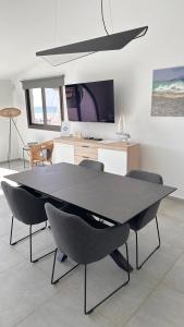 een eetkamer met een tafel, stoelen en een tv bij Villa Sotavento Ocean Views Modern New Apartment in Natural Park in Playa Jandia