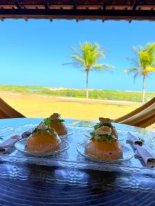 Tres sándwiches en platos sobre una mesa con palmeras. en Paraíso da Barra House, en Cascavel
