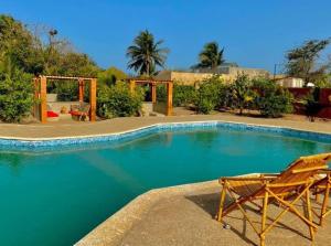 a swimming pool with two chairs sitting next to it at Hôtel Nanaay in Palmarin