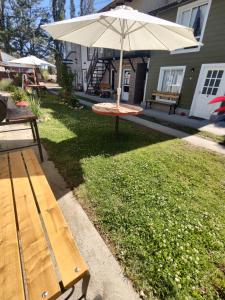 ein Picknicktisch mit Sonnenschirm in einem Hof in der Unterkunft ACOL Habitaciones individuales in Perito Moreno