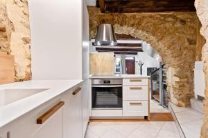 a kitchen with white cabinets and a stone archway at Charming Grund Retreat Near Neumünster Abbey in Luxembourg