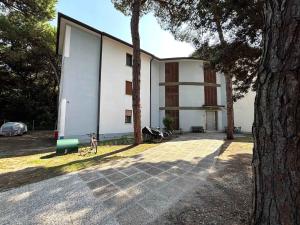 a white building with a tree in front of it at Apartment in Rosolina Mare 54758 in Rosapineta