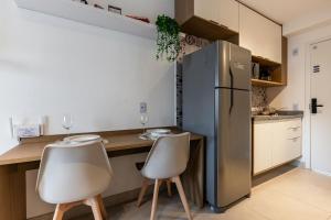 Il comprend une cuisine équipée d'un réfrigérateur en acier inoxydable et de 2 chaises. dans l'établissement Studio na Liberdade | Piscina, Varanda, Wi-Fi, AC, à São Paulo