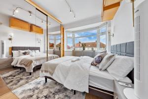 two beds in a room with two windows at Quincy's Homes in Dartford