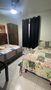 1 Schlafzimmer mit 2 Betten und einem Fenster mit schwarzen Vorhängen in der Unterkunft Condomínio Bezerra in Maragogi