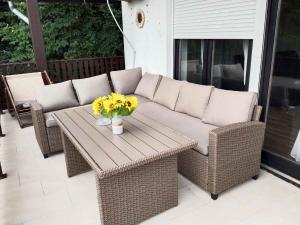 a wicker couch and a table with flowers on a patio at Holiday home in Balatonlelle 54843 in Balatonboglár Vasútállomás
