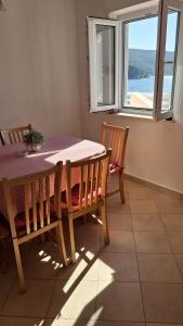een eetkamer met een tafel en stoelen en een raam bij Apartments Dijana in Slano