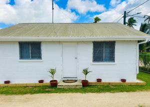 ein weißes Haus mit zwei Topfpflanzen davor in der Unterkunft Pearl Cottage - 2 Bedroom Entire Place in Nuku‘alofa + 2 Fotos