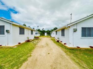 eine unbefestigte Straße zwischen zwei weißen Gebäuden mit Pflanzen in der Unterkunft Pearl Cottage - 2 Bedroom Entire Place in Nuku‘alofa